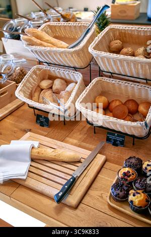 Une exposition abondante de pains et de pâtisseries fraîchement cuits sur une table en bois mettant en valeur une atmosphère chaleureuse de petit déjeuner Banque D'Images