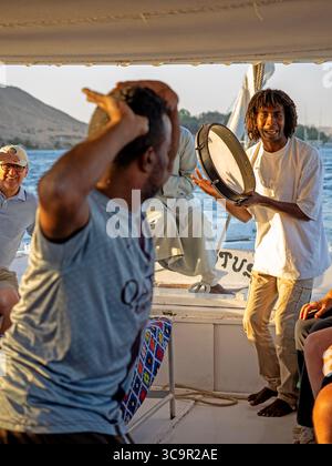 Membres d'équipage divertissant les touristes sur une felouque sur le Nil à Assouan Banque D'Images