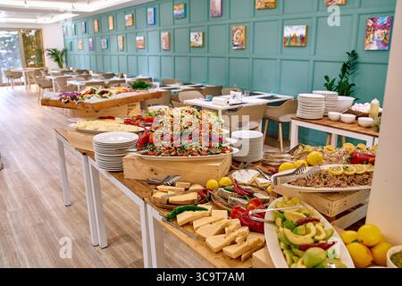 Un buffet abondant avec des salades colorées, des légumes frais, des fromages, des fruits et des éléments décoratifs dans un charmant espace de restauration Banque D'Images