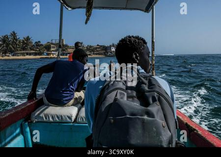 6 avril 2020, île de Ngor, Sénégal : les jeunes traversent en taxi une tranchée pour se rendre sur l’île de Ngor. Depuis quelques semaines, les touristes n’ont pas traversé pour écouter les vagues qui ont frappé la petite île de Ngor au nord de Dakar, le covid-19 est là ! Les commerces et les hôtels sont fermés comme les bordels qui bordent les petites ruelles des entrées de la plage de l'île de Ngor. (Crédit image : © Sadak Souici/ZUMA Press Wire) Banque D'Images