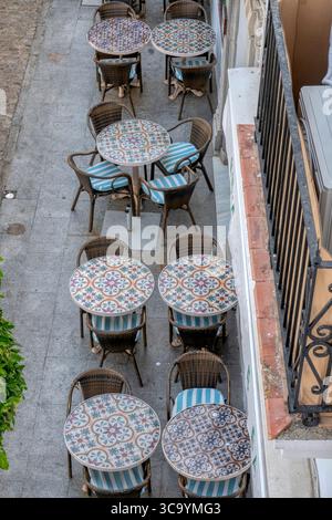 Vue aérienne de charmantes tables de bar bordant une rue pittoresque à Vejer de la Frontera, Cádiz, Andalousie, Espagne - parfait pour un après-midi ensoleillé. Banque D'Images