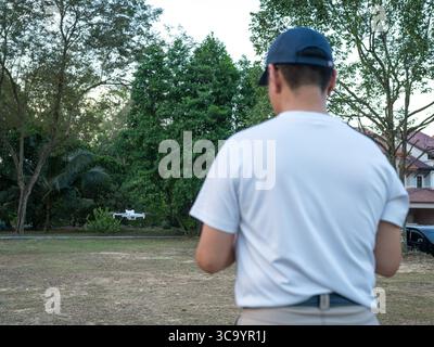 Vue arrière de l'homme exploitant un drone en extérieur. Banque D'Images