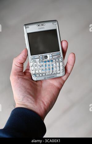Milan, Lombardie, Italie - 10 février 2025 : main présentant un téléphone mobile Nokia E61 vintage, mettant en valeur son design rétro et la marque Vodafone, Highl Banque D'Images