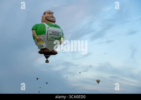 Chambley, France - 30 juillet 2025 : vue d'un ballon géant de peintre de dessins animés au milieu du vaste ciel Azur, parsemé de petits ballons, créant un spectacle fantaisiste. Banque D'Images