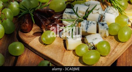 fromage, dattes, raisins, planche à fromage, apéritif, snack, nourriture, été, table en bois, rustique, extérieur, terrasse, pique-nique, raisins verts, plateau de fromages Banque D'Images