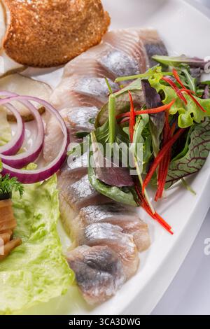 Hareng avec oignons, salade et herbes. Banque D'Images