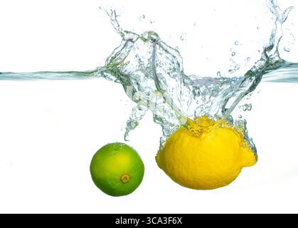 Effet éclaboussure dynamique créé par le citron frais et la chaux immergés dans l'eau claire, capturant la fraîcheur et la vitalité des agrumes. Banque D'Images