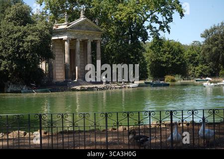 Une vue sereine sur le temple d'Asclépius sur une petite île dans le lac artificiel (Laghetto di Villa Borghese) avec des chaloupes disponibles pour les visiteurs. Banque D'Images