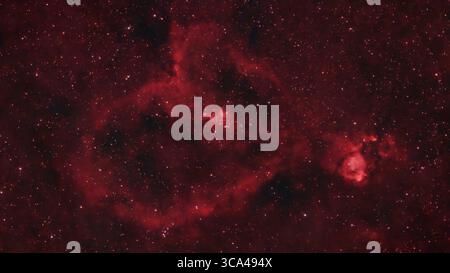 Londres, Royaume-Uni. 6 août 2025. Dans le ciel clair directement au-dessus de Londres, IC 1805 - la nébuleuse du cœur - est photographié avec un télescope intelligent équipé d'un filtre à bande étroite pour couper à travers la pollution lumineuse sur une période de 3 heures. La nébuleuse d'émission rouge incandescente est distante de 7 500 années-lumière de la Terre dans la constellation de Cassiopée. Au centre de la nébuleuse du cœur se trouve l'amas d'étoiles ouvert Melotte 15 qui éclaire le nuage de gaz environnant. Crédit : Malcolm Park/Alamy Banque D'Images