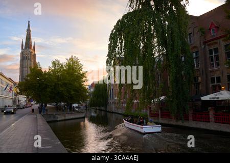 Bruges, Belgique – 12 septembre 2024 - croisière en soirée sur les canaux près de l'église notre-Dame de Bruges Belgique. Les touristes naviguent sur le canal de Dijver. Banque D'Images