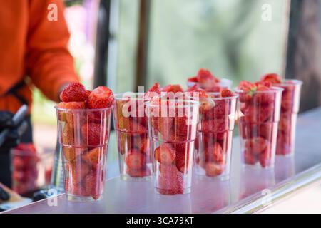 Beaucoup de fraises fraîches dans des verres en plastique à vendre dans un marché aux fruits en plein air. Nourriture saine de rue. Banque D'Images