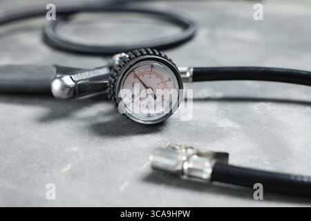 Un pistolet de gonflage de pneu avec jauge sur fond gris, gros plan Banque D'Images