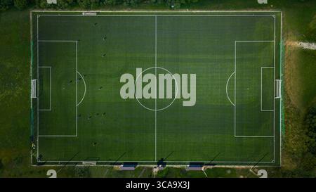 Vue aérienne de haut en bas d'un terrain de football vert avec des joueurs visibles et des marques blanches nettes sous la lumière du jour Banque D'Images