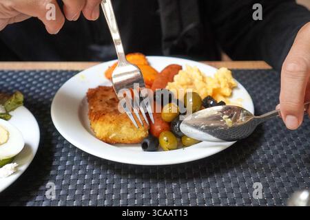 Petit déjeuner copieux composé d'œufs brouillés, de saucisses grillées et de garnir sur une assiette blanche. Banque D'Images
