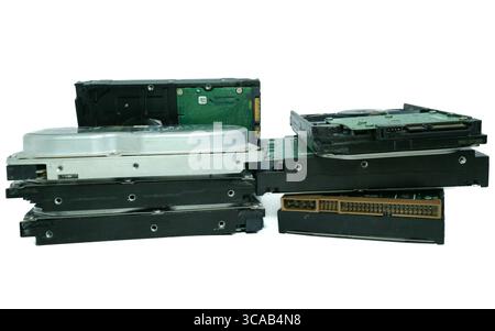 Pile de grands disques durs obsolètes avec de vieux connecteurs, disposés sur fond blanc de studio, symbolisant les déchets électroniques et la technologie obsolète. Banque D'Images