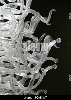 SEATTLE - APR 25, 2025 - lustre en verre complexe avec des formes fluides et tourbillonnantes, créant un affichage élégant et artistique contre une grotte sombre Banque D'Images