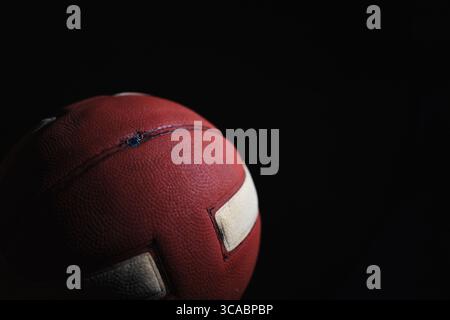 Gros plan d'un ballon de basket rouge avec des rayures blanches sur fond noir Banque D'Images