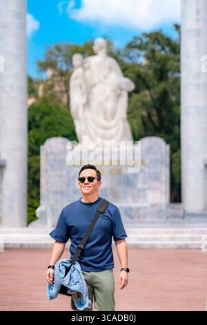 Le jeune homme heureux Latino Smile porte un t-shirt bleu marine, un pantalon olive, des lunettes de soleil noires et un sac décontracté tout en se tenant fièrement debout à Chapultepec, Mexico Banque D'Images