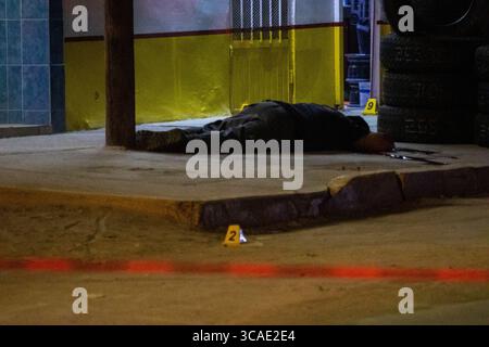 Une scène tragique à Ciudad Juarez : une personne gît sans vie dans un garage, entourée de marqueurs de preuves. Banque D'Images