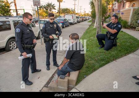 4 juillet 2017, Costa Mesa, Californie : Costa Mesa, CA, les policiers montrent une citation à signer pour un suspect après l'avoir appréhendé pour utilisation de feux d'artifice illégaux le 4 juillet. Note officier photographiant l'incident avec un appareil photo de téléphone portable à droite. (Crédit image : © Spencer Grant/ZUMA Press Wire) Banque D'Images