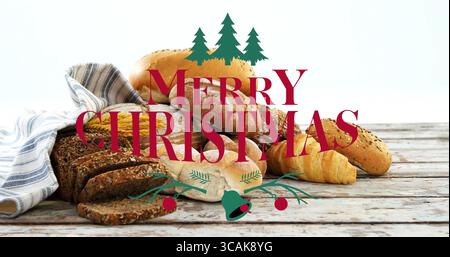 Affichage pain ensemencé, baguette, croissant et rouleaux sur la table en bois, avec superposition Joyeux Noël Banque D'Images
