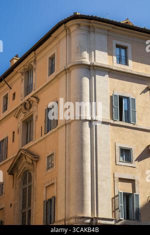 Fenêtres sur un bâtiment jaune surplombant les rues romaines, les fenêtres de couleur dorée donnent sur les rues romaines intemporelles, où l'histoire rencontre la vie quotidienne Banque D'Images