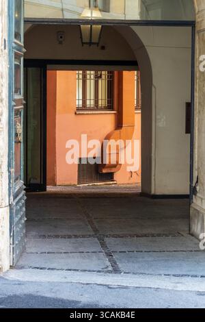 Passage en pierre voûtée menant à une cour ensoleillée dans un bâtiment méditerranéen, un mélange de charme architectural et d'élégance tranquille Banque D'Images