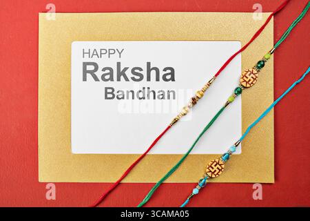 Gros plan de rakhis colorés avec un message de Happy Raksha Bandhan sur le papier avec un fond coloré. Célébrer le lien de l'amour et du protec Banque D'Images