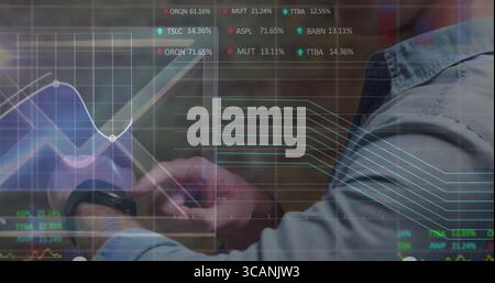 Homme portant chemise en denim et smartwatch tapotant tablette dans le bureau, avec graphiques financiers, espace de copie Banque D'Images