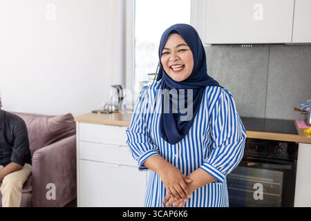Femme musulmane debout dans la cuisine moderne portant le Hijab Banque D'Images