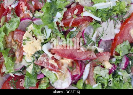 Les feuilles de légumes verts frais, les œufs et les tomates finement hachées pour la salade de printemps. Macro vue de dessus en studio Banque D'Images