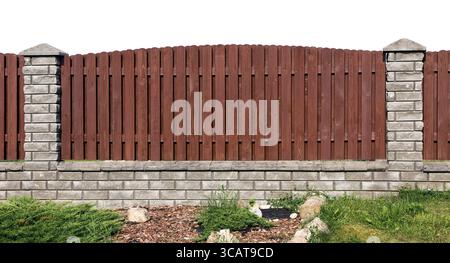 Fragment de clôture rurale idéal fait de planches brunes en bois et de briques grises. Isolé Banque D'Images