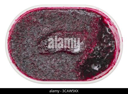 La confiture de cassis congelés au réfrigérateur dans un récipient en plastique. Isolé avec vue sur la partie supérieure du chemin macro Banque D'Images