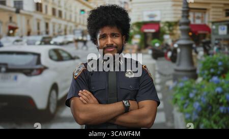 Policier avec les bras croisés se tient confiant sur une rue animée de la ville, entouré de voitures et de bâtiments, mettant en valeur la vie urbaine dans un s en plein air Banque D'Images