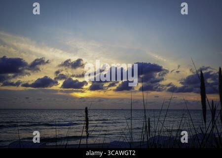 Lever de soleil sur la mer avec des nuages spectaculaires et des vagues douces sous un ciel coloré. Le rivage de la mer Baltique en 18586 Goehren sur l'île de Ruegen Banque D'Images