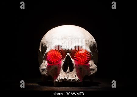 Concept de coronavirus COVID-19. Red virus Coronavirus modèle dans les yeux du crâne sur fond noir. Banque D'Images