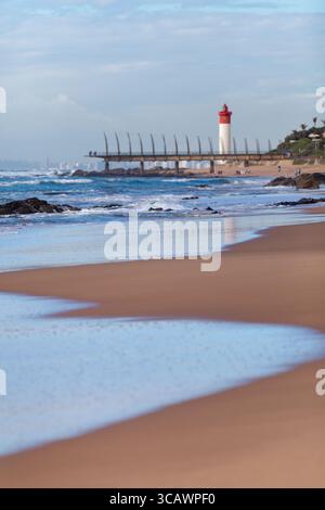 Umhlanga Rocks plage avec le phare et la célèbre jetée d'os de baleine en arrière-plan. Banque D'Images