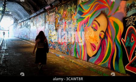 Marcher devant une partie du tunnel Graffiti à Leake Street, dans le centre de Londres, à l'été 2025. Banque D'Images