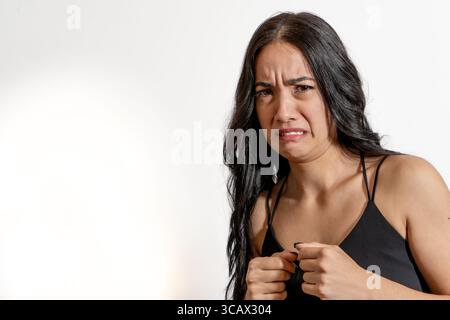 Portrait en studio d'une jeune femme latine faisant une grimace dégoûtée, exprimant une forte aversion ou révulsion Banque D'Images