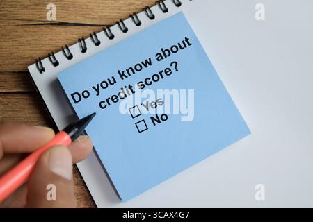 Savez-vous au sujet de score de crédit écrire sur des notes autocollantes isolé sur la table en bois. Une personne répond au concept de question Banque D'Images