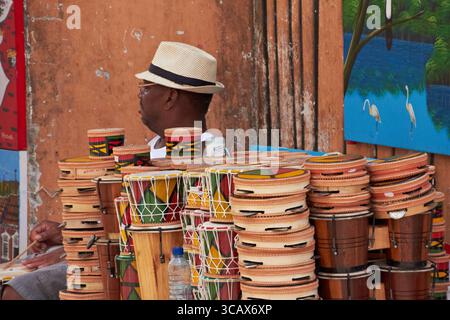 Vendeur de rue affichant des instruments colorés de percussion faits à la main dans un marché dynamique à Salvador, Brésil Banque D'Images