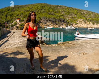 Bisevo, Croatie - 9 septembre 2023 : une femme en haut rouge et en short noir marche le long de la jetée, profitant de la journée ensoleillée. Banque D'Images
