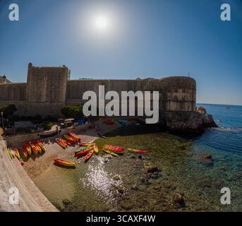 Dubrovnik, Croatie - 12 septembre 2023 : kayaks assis sur la plage, prêts pour une excursion au coucher du soleil. Les gens se rassemblent, se préparant à se lancer dans une aventure pittoresque. Banque D'Images