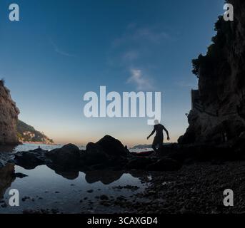 Dubrovnik, Croatie - 12 septembre 2023 : un homme marche sur les rochers pour monter dans son kayak pour une excursion au coucher du soleil sur la mer Adriatique. Banque D'Images