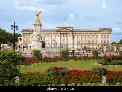 La façade du palais de Buckingham et le mémorial Victoria, vus à travers les jardins de fleurs formels un jour d'été à Londres, Royaume-Uni. Banque D'Images