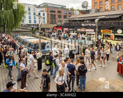 Des foules de touristes et d'habitants explorent les stands de nourriture de rue animés le long du Regent's canal dans le célèbre marché de Camden, Londres, Royaume-Uni. Banque D'Images