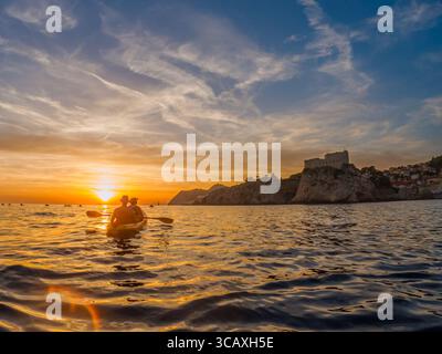 Dubrovnik, Croatie - 12 septembre 2023 : les kayakistes pagayent dans le coucher du soleil lors d'une visite guidée. Ils apprécient le beau paysage et les eaux calmes. Banque D'Images