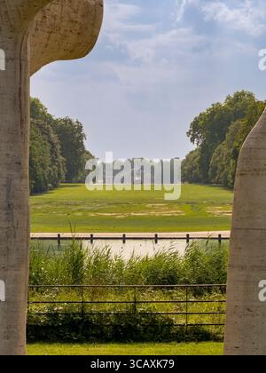 En regardant à travers la sculpture monumentale en pierre « The Arch » de Henry Moore vers la statue de l'énergie physique dans les jardins de Kensington, Londres, Royaume-Uni. Banque D'Images
