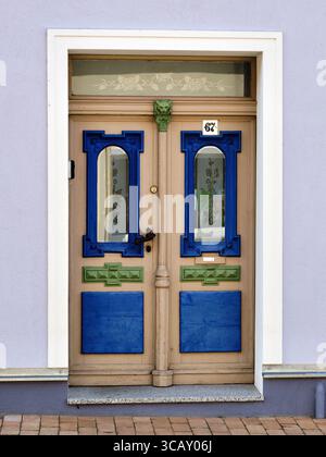 Porte décorative beige avec des panneaux peints bleus et verts frappants et des détails en verre floral, photographiée à Vorpommern, Allemagne. Partie de la série « c Banque D'Images