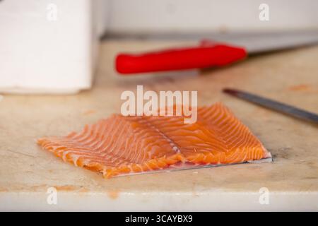 Filet de saumon frais préparé sur une planche à découper de cuisine, prêt pour la cuisson. Une étape commune dans la préparation de la nourriture à la maison, idéal pour sain et savoureux Banque D'Images